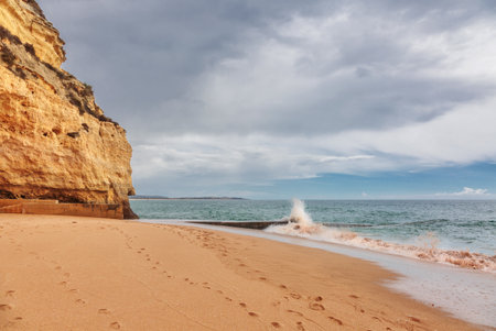 Sandy beach with stony ridges overcast weather view on Atlantic rocky coast, Algarve, Portugal.の写真素材