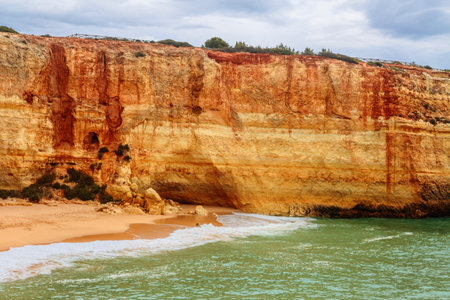 Sandy beach with stony ridges overcast weather view on Atlantic rocky coast, Algarve, Portugal.の写真素材