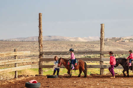 JERUSALEM, ISRAEL - DECEMBER 28, 2016: Children are taught to ride horses on a farm in the village of Tekoa near Jerusalem.のeditorial素材