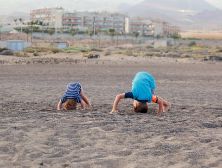 Boy and girl standing on their heads on the beach. Tenerife island, Spainの写真素材