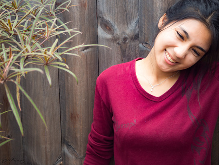 Asian woman standing and have a big smile, wooden backgroundの写真素材