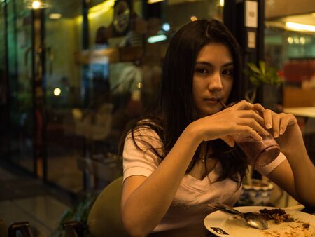 Asian woman drinking a blueberry smoothiesの写真素材