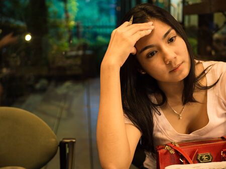 Asian woman sitting on the chair and thinking something