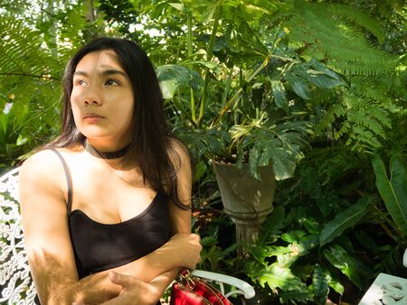 Asian woman sitting on the wooden chair in the gardenの写真素材