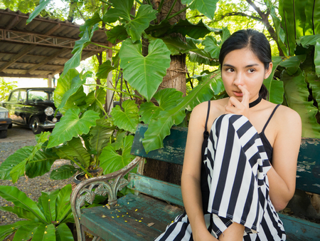 Asian woman sitting on the wooden chair in the gardenの写真素材