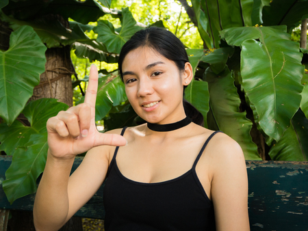 Asian woman sitting on the wooden chair in the gardenの写真素材