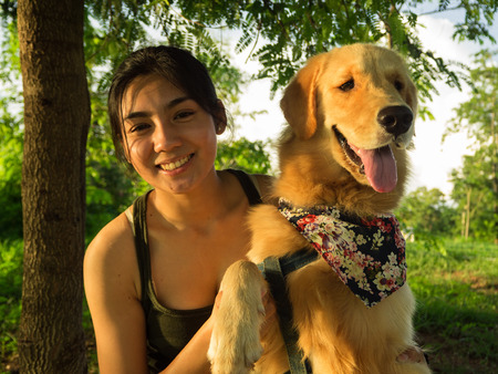 Golden retriever and Asian woman are playing in the parkの写真素材