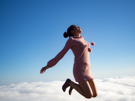 Asian woman jumping and have a big smile, sea of fog backgroundの写真素材