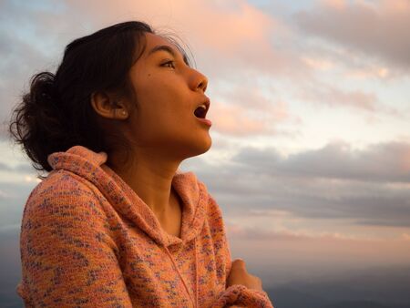 Asian woman opening her mouth, cool feeling, sunset sky background