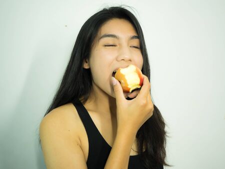 Asian woman eating red apple on white backgroundの写真素材