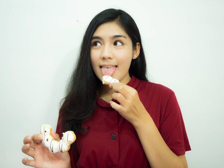 Asian woman holding donut on white background, red shirt, black long hairの写真素材