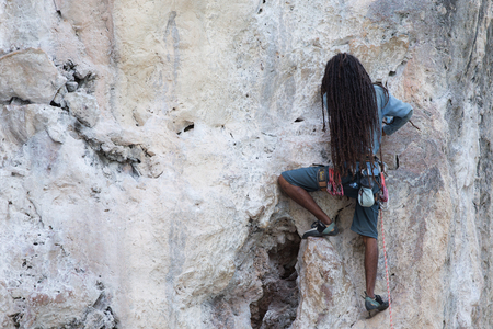 A young man with a rope engaged in the sports of rock climbing on the rockの写真素材