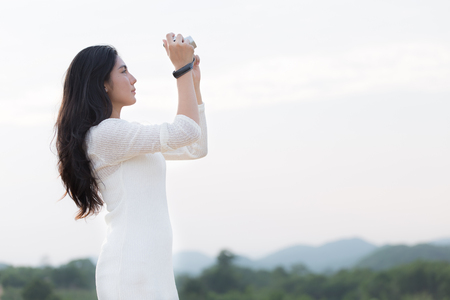 Asian woman photographer is taking a picture of skyの写真素材