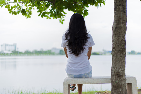 Asian woman lonely in the park sitting in the rock chair . woman lonely concept.の写真素材
