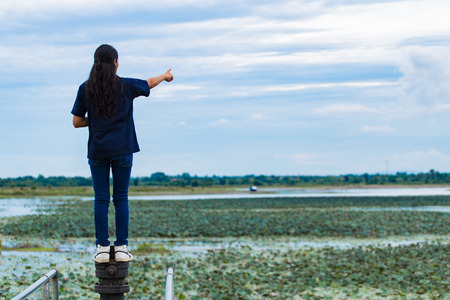 Young beautiful Asian girl standing on jetty forest and river on backgroundの写真素材