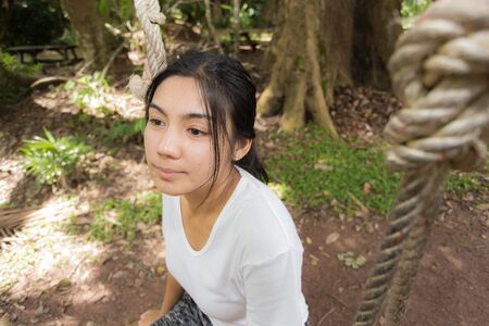 Young woman is swinging on a swing in summer topical forestの写真素材