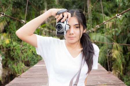 Beautiful young asian woman taking photos outdoors in a forestの写真素材