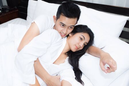 Young loving couple on the bed in the morningの写真素材