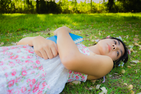 Pretty young asian woman picnic on the meadow with her book and relaxing in the parkの写真素材