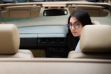 A portrait of a beautiful young asian woman wearing glasses and she is in the red carの写真素材