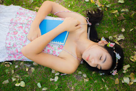 Pretty young asian woman picnic on the meadow with her book and relaxing in the parkの写真素材