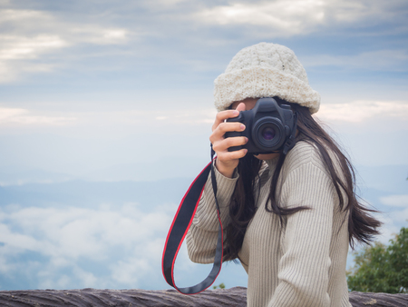 Asian woman photographer taking photo of landscape from top of the mountain in the morning with sunriseの写真素材