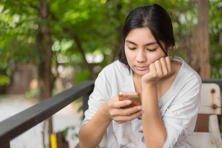Beautiful asian woman playing with smartphone in cafe shopの写真素材