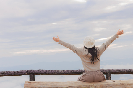 Beautiful asian woman relaxing on top of a mountain and enjoying sunrise, open her armsの写真素材