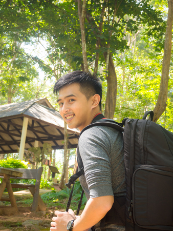 Handsome asian man with backpack taking a photo with mirrorless camera.の写真素材