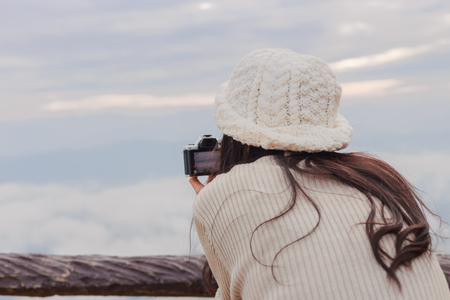 Asian woman photographer taking photo of landscape from top of the mountain in the morning with sunriseの写真素材