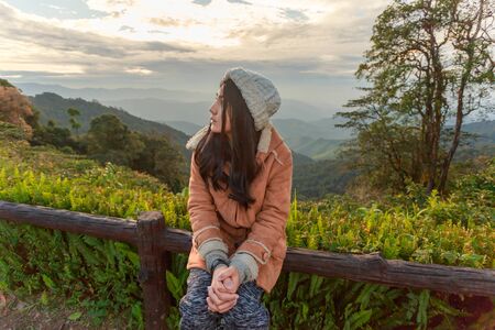 Beautiful asian woman relaxing on top of a mountain and enjoying sunriseの写真素材