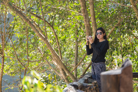 Beautiful asian woman with backpack taking a photo with mirrorless camera.
