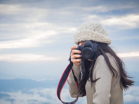 Asian woman photographer taking photo of landscape from top of the mountain in the morning with sunriseの写真素材