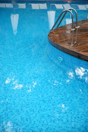 Fragment of swimming pool with a ladder and transparent water
