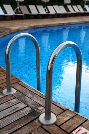 Fragment of swimming pool with a ladder and transparent water