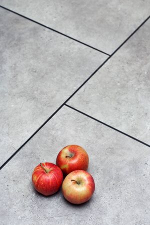 red apples, on grey floor tiles with black seamsの写真素材