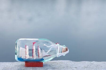 miniature ship inside a bottle, on sea background.の写真素材