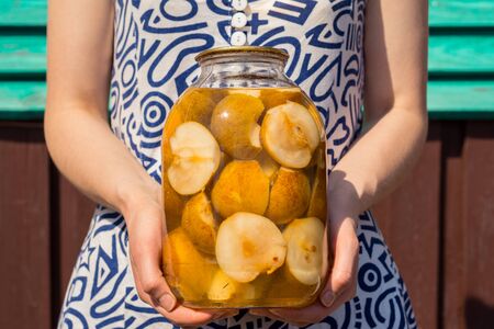 pear juice with pears in a jar in the hands of a young girlの写真素材