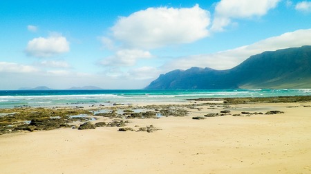 Beach and Mountains - beautiful coast in Caleta de Famara, Lanzarote Canary Islands. Beach in Caleta de Famara is very popular among surfers.の写真素材