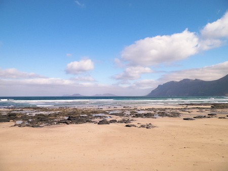 Beach and Mountains - beautiful coast in Caleta de Famara, Lanzarote Canary Islands. Beach in Caleta de Famara is very popular among surfers.の写真素材