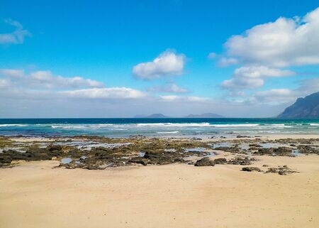 Beach and Mountains - beautiful coast in Caleta de Famara, Lanzarote Canary Islands. Beach in Caleta de Famara is very popular among surfers.の写真素材