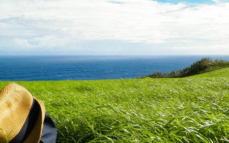 Backpack and hat on meadow. Sao Miguel Island. Azores. Travel and nature concept.
