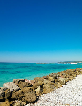 Brakwater made of stones on beach in Vada, transparent, turquoise water. Travel and nature of Tuscany concept.の写真素材