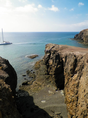 Sport, nature and leisure concept. Yacht boat close to coastal cliffs of Lanzarote island. Crystal clean Atlantic Ocean water.の写真素材