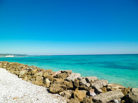 Brakwater made of stones on beach in Vada, transparent, turquoise water. Travel and nature of Tuscany concept.の写真素材