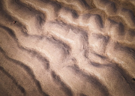 Traces of waves on sand as a natural background. Copy space. Abstract filter toned.