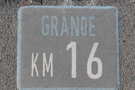 Imprint of the number sixteen on a tarmac pavement.の写真素材