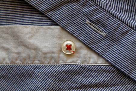 Closeup of blue and white stripped fabric texture with button