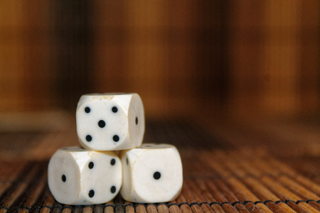 Stack of three white plastic dices on brown wooden board background. Six sides cube with black dots. Number 4, 5, 1の写真素材