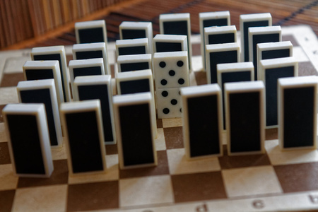 Domino pieces in a row and one different statnd, back side, on the bamboo brown wooden table...